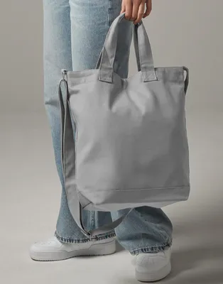 A person is holding a gray canvas tote bag.