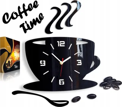 A black acrylic wall clock shaped like a coffee cup with steam rising from it, along with decorative coffee beans and a spoon. The clock has white hour markers and hands. A product box is visible on the left.