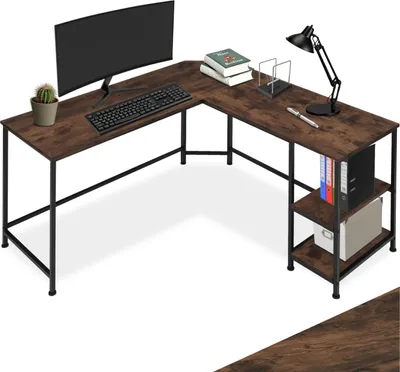 A corner desk with a computer, keyboard, lamp, books, and a plant.