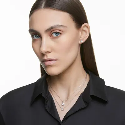 A woman wearing jewelry, including earrings and necklaces.