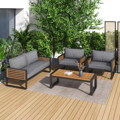 An outdoor patio set with a sofa, two chairs, and a coffee table, surrounded by lush greenery.
