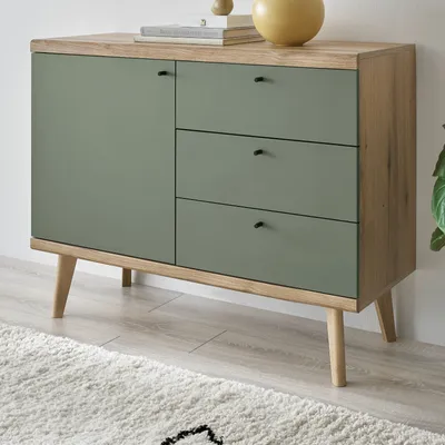 A close-up view of a green and wood sideboard with three drawers and a cabinet door, resting on wooden legs.