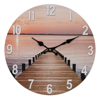 A round wall clock with a sunset and pier image, featuring black clock hands and silver numbers.