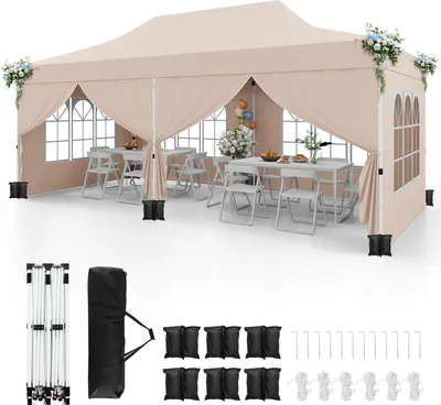 A beige pop-up canopy tent set up with tables and chairs inside, with accessories laid out below.