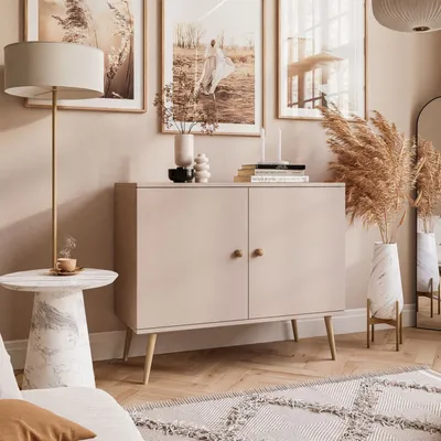 A well-decorated living room scene featuring a beige cabinet, side table with a coffee cup, floor lamp, artwork, and decorative plants.