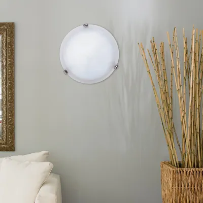 A round ceiling light fixture is mounted on a light gray wall, next to a decorative basket of bamboo stalks. A portion of a white sofa and a framed mirror are visible on the left side of the image.