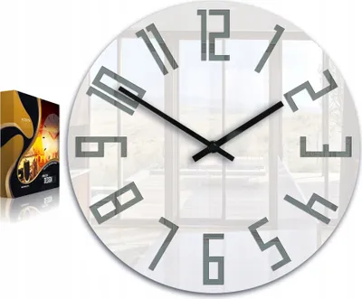 A modern wall clock with abstract numbers, displayed in front of a window.