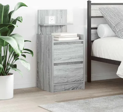 A bedside table with drawers and shelves is placed next to a bed, with a plant in a pot to the left.