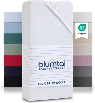 A stack of folded fitted sheets in various colors, with a white fitted sheet prominently displayed in the foreground, featuring brand and material information.