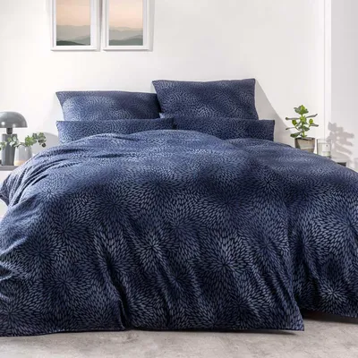 A neatly made bed with blue patterned bedding.