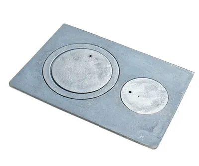 A top-down view of a cast iron stove plate with two circular openings.