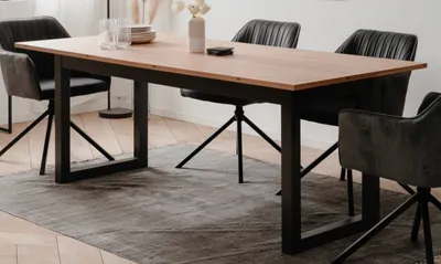 A dining table and chairs set in a room with a rug.