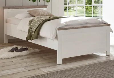 A bedroom scene with a single bed, bedding, and a rug with shoes.