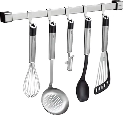 A set of kitchen utensils hanging on a magnetic rail.