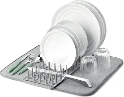 A dish drying rack with plates, glasses, and cutlery on a mat.