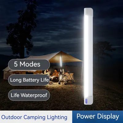 People camping at night with a tent illuminated by a long light bar.