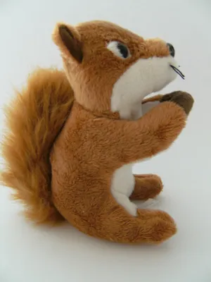 A plush toy squirrel sitting on a white surface.