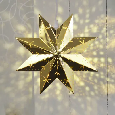 A gold star-shaped lamp with cutouts casting light patterns on a white background.
