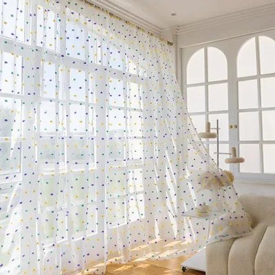 A room with large windows covered by sheer curtains with polka dots.