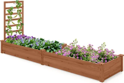 A long, wooden raised garden bed with two sections, filled with purple and pink flowers and a trellis with green vines on one end.