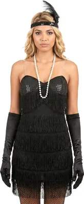 A woman modeling a black flapper-style dress with fringe and sequins, pearl necklace, and long black gloves.