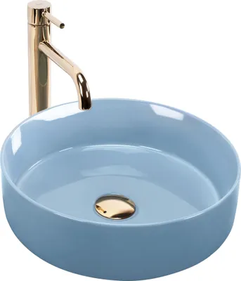 A light blue ceramic vessel sink with a gold faucet and drain.