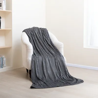 A gray blanket draped over a white armchair in a room with a bookshelf and a window.