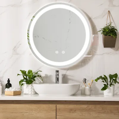 A modern bathroom vanity with a round LED mirror, a vessel sink, and plants.
