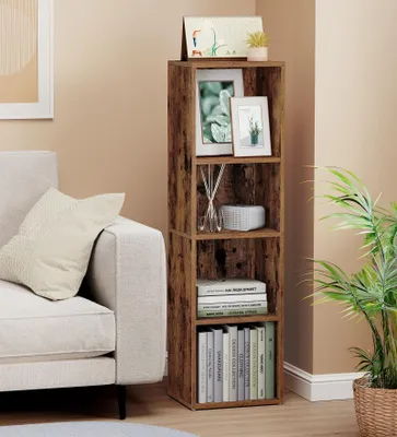 A tall, narrow, rustic brown bookshelf with four shelves is placed next to a light-colored sofa in a living room. Decorative items and books are displayed on the shelves. A potted plant is visible to the right of the bookshelf.