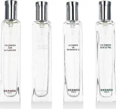 Four clear glass perfume bottles with silver caps, arranged side-by-side against a white background.