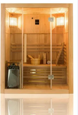 A wooden sauna with glass doors, featuring benches, a bucket, and stones.