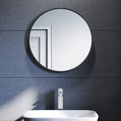 A round mirror above a sink in a bathroom.