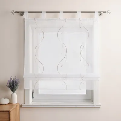 A white sheer curtain with a wavy embroidered pattern hangs on a window.