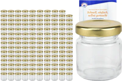 A stack of small glass jars with gold lids and a single jar with a gold lid and a small booklet.