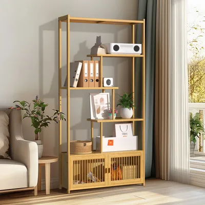 A bamboo bookshelf filled with various items, placed in a room next to a sofa and a window.