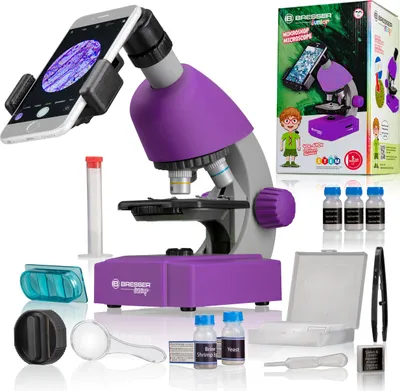 A BRESSER JUNIOR microscope set with accessories, including a smartphone adapter, sample slides, and bottles of specimen.