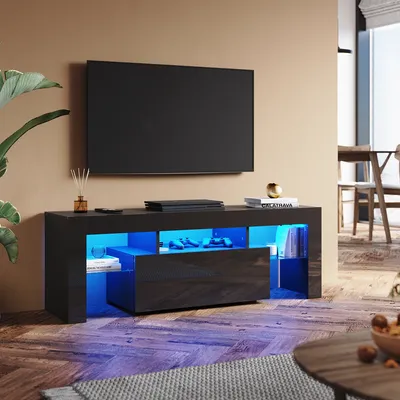 A modern living room with a black high-gloss TV stand featuring RGB lighting, a television, and decorative items.
