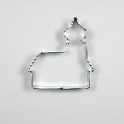 A metal cookie cutter shaped like a church is placed on a white background.