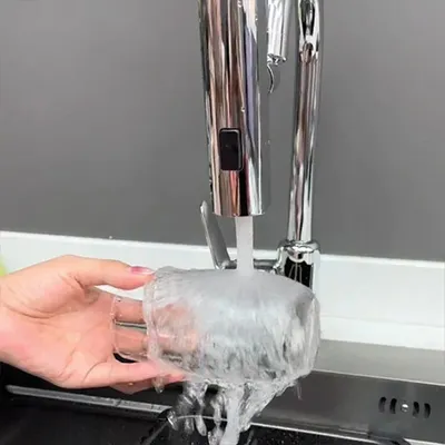 A hand holding a glass under a faucet with water running.