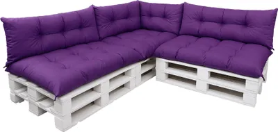 A sectional sofa made from white wooden pallets with purple cushions.