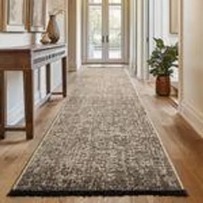 A long hallway with a runner rug, a console table, and a potted plant.