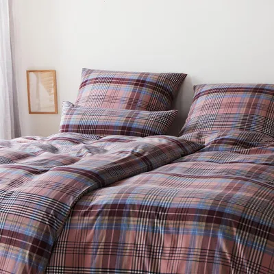 A close-up view of a plaid patterned duvet cover and pillowcase set on a bed.