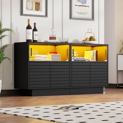 A modern black sideboard with yellow interior lighting, displaying books, a radio, wine bottles, and decorative items.