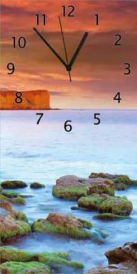 Produktbild von Wallario Design Wanduhr bedruckt, Größe 30 x 60 cm, Motiv: Sonnenaufgang am Meer mit Landzunge und Felsen im Wasser