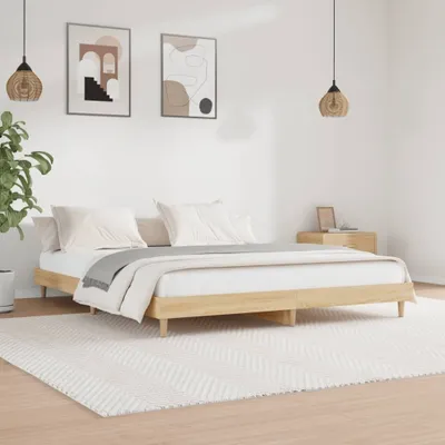A bedroom scene with a wooden bed frame, bedding, two framed pictures on the wall, and pendant lights.