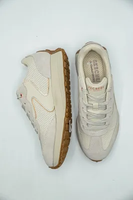 A pair of cream-colored Skechers sneakers are displayed on a white background.
