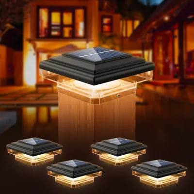A group of solar-powered fence post lights are displayed in front of a blurred house at dusk.