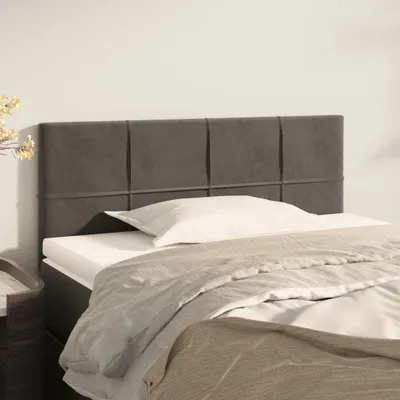 A close-up view of a dark gray upholstered headboard with a white pillow and beige bedding.