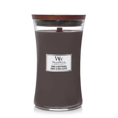 A WoodWick Sand & Driftwood scented candle in a glass jar with a wooden lid.
