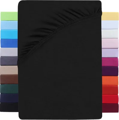 A black fitted sheet is shown laid flat, with a stack of fitted sheets in various colors visible on the left and right sides.